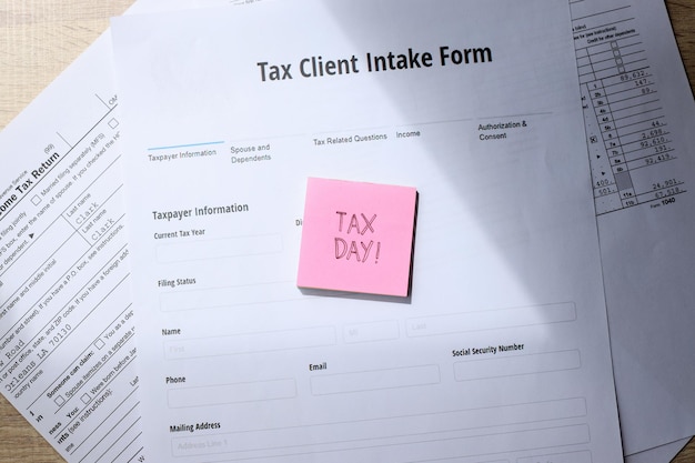 Formularze podatkowe z dniem podatkowym zapisane na karteczce samoprzylepnej