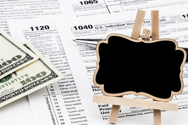 Formularze podatkowe z pieniędzmi, długopisem i tablicą z miejscem na tekst.