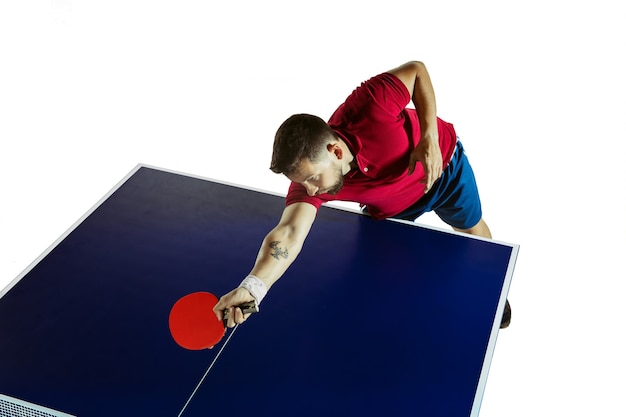 Forsowne. Młody człowiek gra w tenisa stołowego na białej ścianie. Modelka gra w ping ponga. Pojęcie wypoczynku, sportu, ludzkich emocji w rozgrywce, zdrowego stylu życia, ruchu, akcji, ruchu.