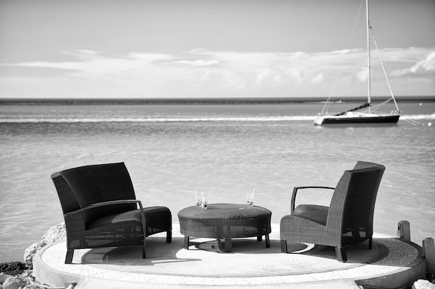 Fotele i stół na tropikalnej plaży w st johns antigua Meble rattanowe i jacht w turkusowej wodzie morskiej lub oceanicznej Letnie wakacje na Karaibach Lounge koncepcja luksusowego stylu życia