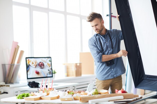 Fotograf dostosowujący światło na planie w Studio