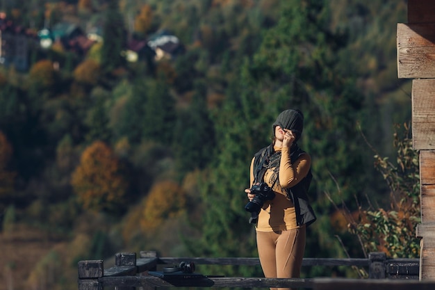 Fotograf kobieta pozuje z aparatem na tle lasu i gór