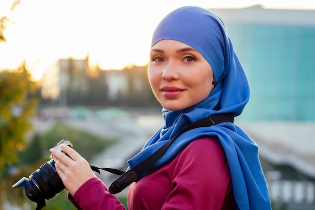Fotograf kobieta ubrana w hidżab. kobieta trzymająca kamerę hobbysta lub dziennikarz w letnim parku jesienne drzewa las