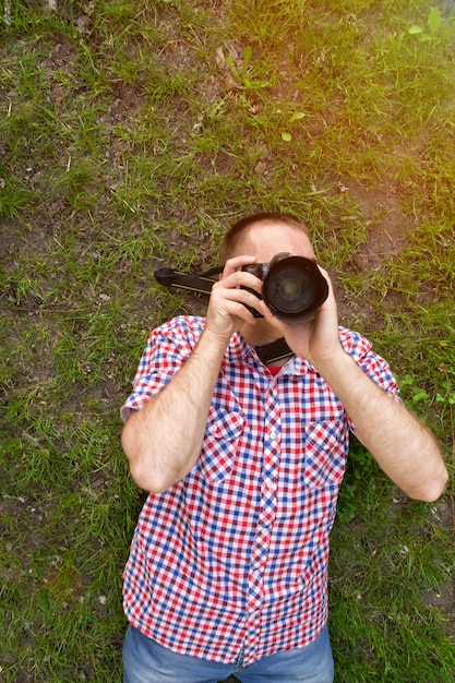 Fotograf leży na trawie i robi zdjęcia.