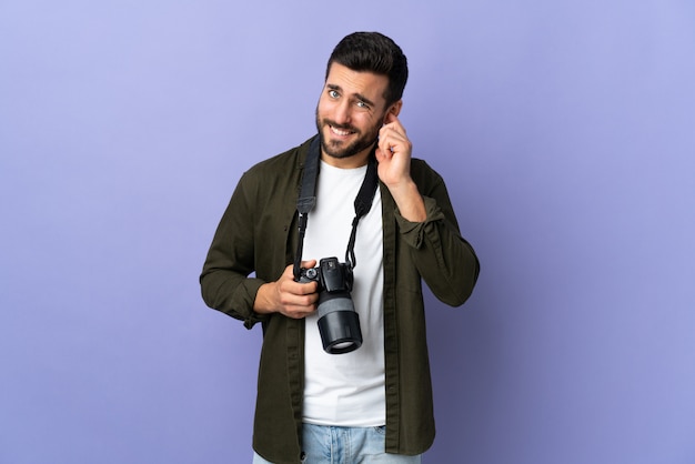 Fotograf mężczyzna na pojedyncze fioletowe ściany sfrustrowane i obejmujące uszy
