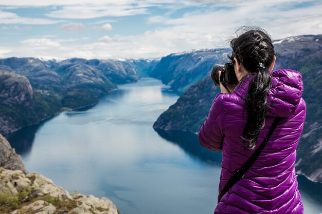 Fotograf przyrody turysta z pędów aparatu, stojąc na szczycie góry. Piękna przyroda Norwegia Preikestolen lub Prekestolen.