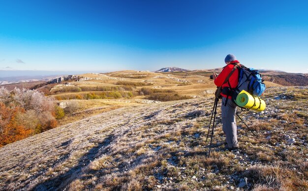 Fotograf robi zdjęcia na szczycie góry jesienią. Podróżnik z plecakiem cieszący się widokiem ze szczytu góry