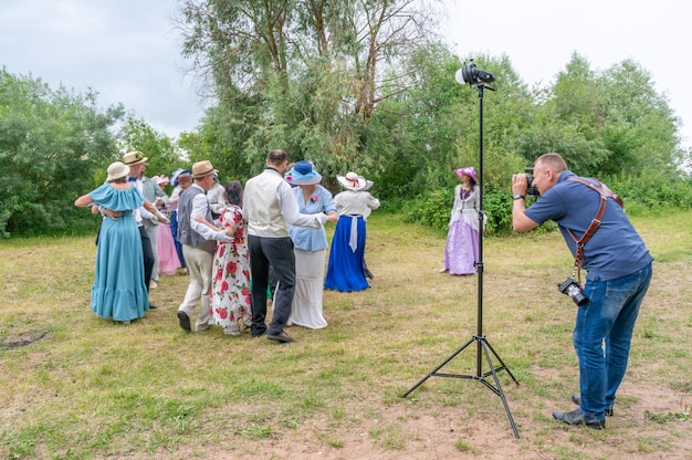 Fotograf robi zdjęcia tańczących ludzi w strojach vintage, na łonie natury