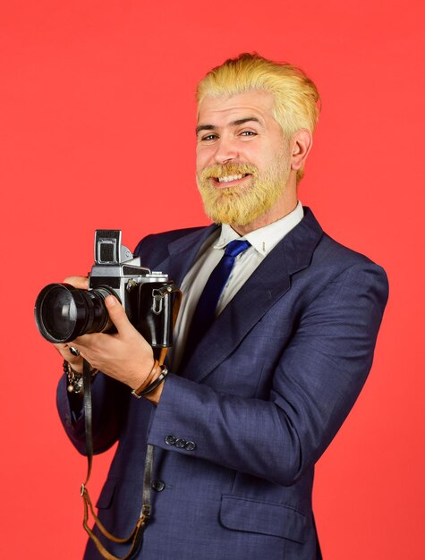 Fotograf trzyma aparat retro Koneser starych wartości Klasyczne i oldschoolowe ustawienia ręczne Fotograf z blond brodą i wąsami Twórca treści Mężczyzna brodaty fotograf hipsterski