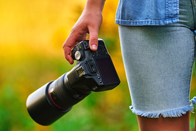 Zdjęcie fotograf trzymający aparat dslr w dłoni zbliżenie o zachodzie słońca