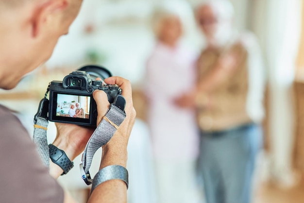 Fotograf Trzymający Aparat I Wykonujący Sesję Zdjęciową Dla Starszej Rodziny