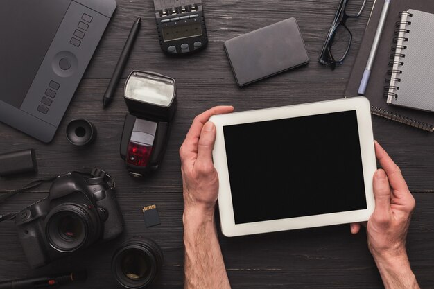 Fotograf używający pustego cyfrowego tabletu w miejscu pracy ze sprzętem fotograficznym, przewijaniem zdjęć, koncepcją technologii i komunikacji, widokiem z góry, przestrzenią do kopiowania