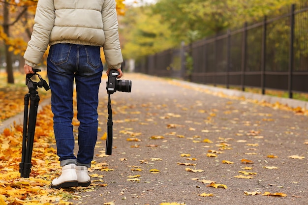 Fotograf z profesjonalnym aparatem i statywem na zewnątrz na jesienny dzień zbliżenie Miejsce na tekst