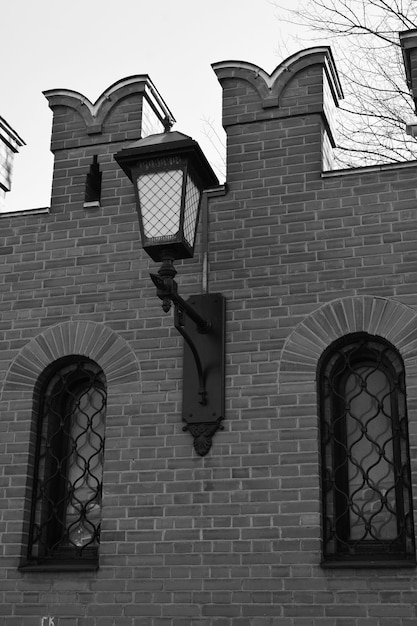Fotografia czarno-biała Łukowate okna w ceglanej ścianie Ładna latarnia na ścianie