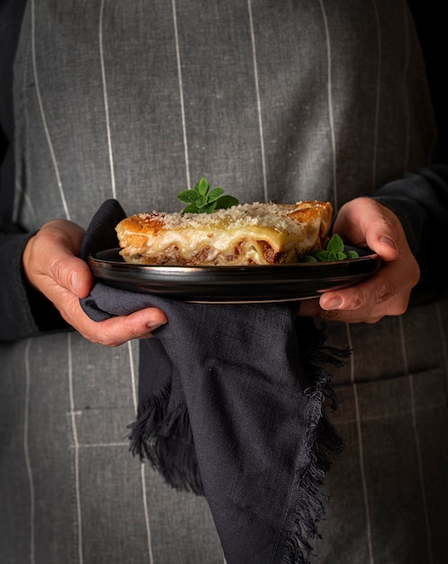 Fotografia kulinarna rąk trzymających lasagne