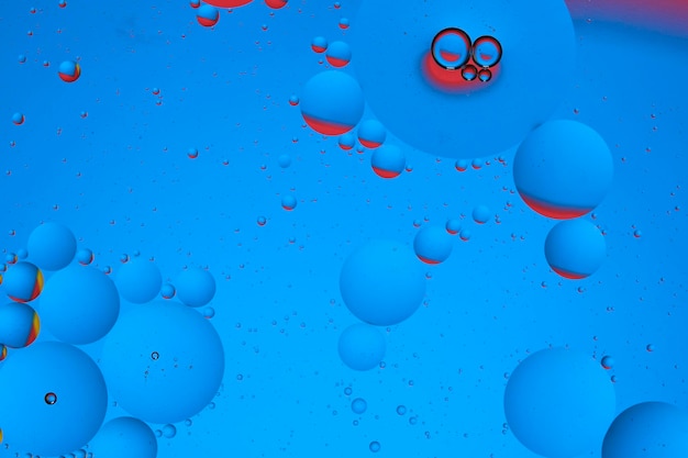 Fotografia makro z kółkami kropelki oleju powierzchnia wody Abstrakcyjne niebieskie i czerwone tło z bąbelkami oleju