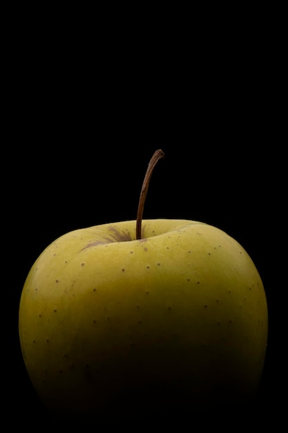 Fotografia makro zielonego jabłka na czarnym tle Obraz pionowy z miejscem na kopię