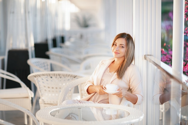 Fotografia modelki na zewnątrz pięknej kobiety o blond włosach w eleganckich ubraniach.