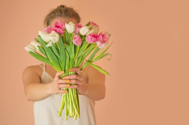 Fotografia w stylu moda ładna dziewczyna w białej sukni z tulipanami.