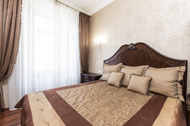 Fotografia wnętrz luksusowa sypialnia z dużym drewnianym łóżkiem w stylu klasycznym