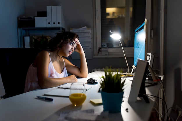 Fotografia zmęczona kobieta pracuje w domu przy nocą póżno.