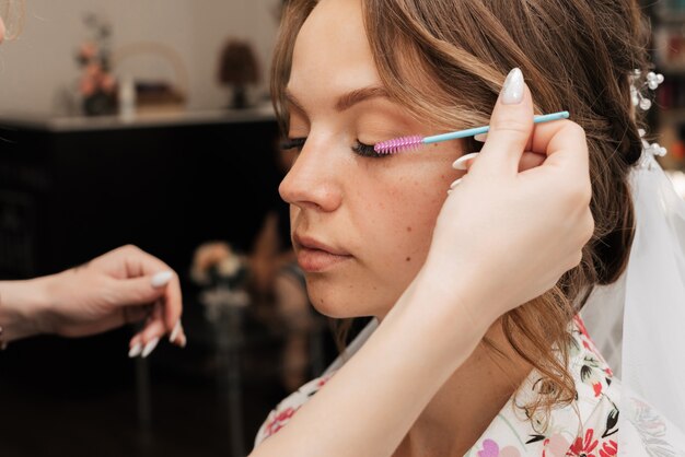 Fotografowanie w salonie kosmetycznym. wizażystka wykonuje makijaż ślubny dla młodej dziewczyny.