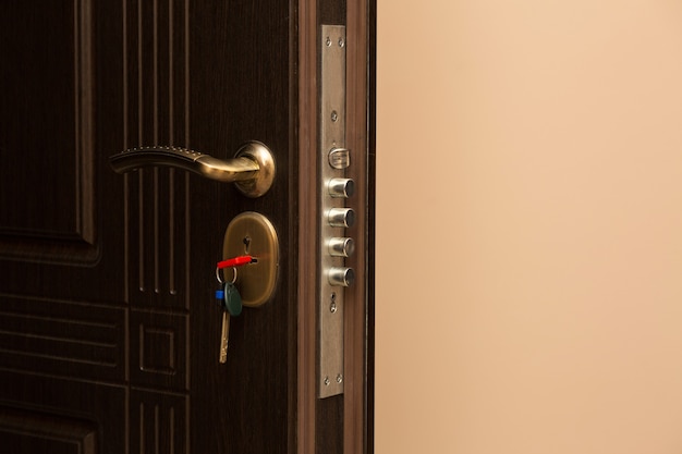Fragment brązowych metalowych drzwi wejściowych z zamkiem i kluczem. Miejsce na tekst
