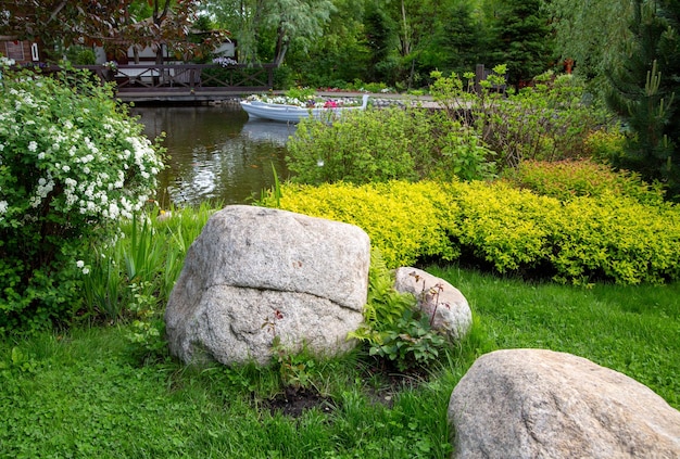 Fragment parku krajobrazowego z roślinami ozdobnymi, stawem i kamieniami