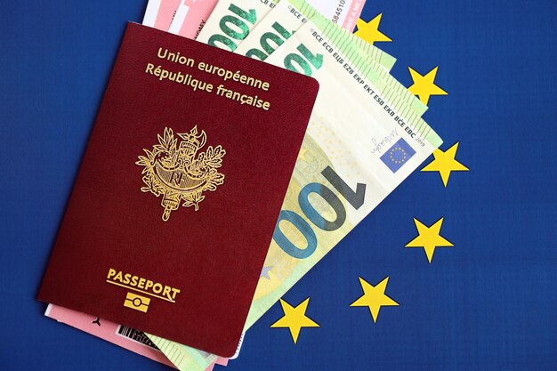 Francuski paszport Unii Europejskiej i bilety lotnicze z pieniędzmi na błękitnym tle