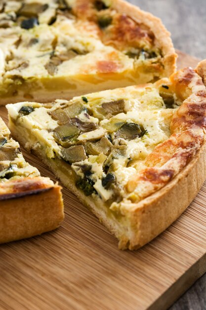 Francuski quiche Lorraine plasterek z warzywami na rustykalnym drewnianym stole.