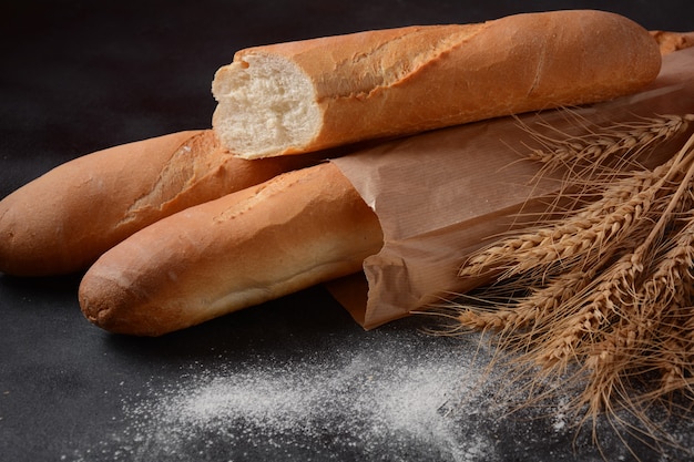 Francuskie bagietki świeżego chleba na ciemnym tle i pszenicy