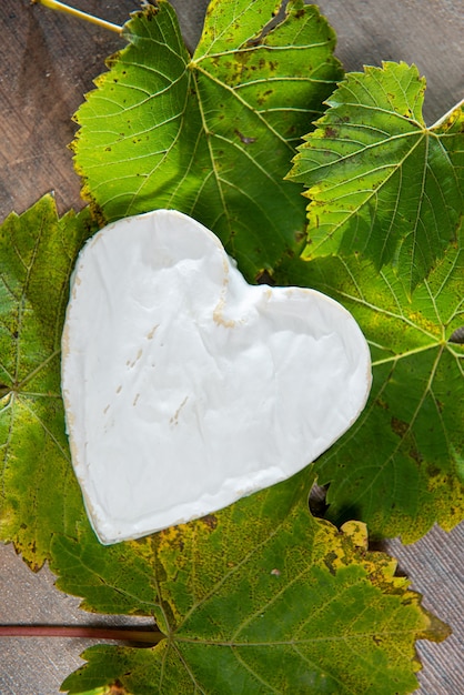 Zdjęcie francuskie serce w kształcie sera neufchatel na jesiennych liściach