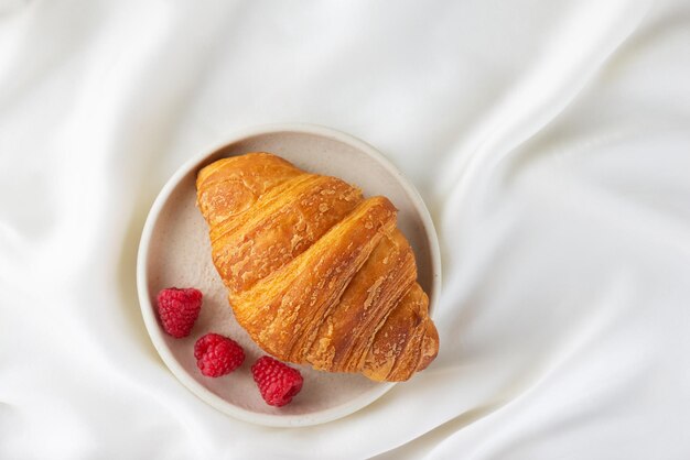 Francuskie śniadanie świeży chrupiący croissant z malinami na talerzu