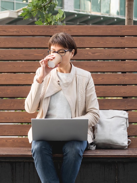 Zdjęcie freelance kobieta pracuje zdalnie z laptopem i pije kawę miejski styl życia millenialsów