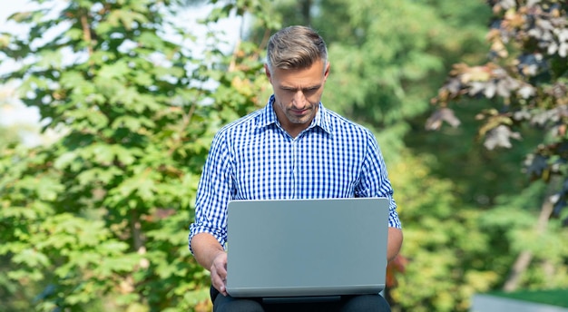 Freelancer pracujący na laptopie mężczyzna freelancer freelancer biznesowy na zewnątrz z miejsca na kopie na komputerze osobistym