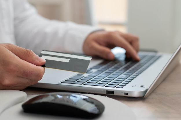 Freelancer używający swojej karty kredytowej przed swoim laptopem próbuje kupić w internecie online