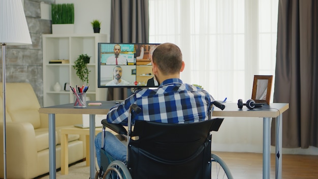 Zdjęcie freelancer z niepełnosprawnością chodzenia na wózku inwalidzkim podczas biznesowej rozmowy wideo online.