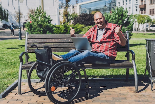 Freelancer z niepełnosprawnością ruchową na wózku inwalidzkim pracujący w parku