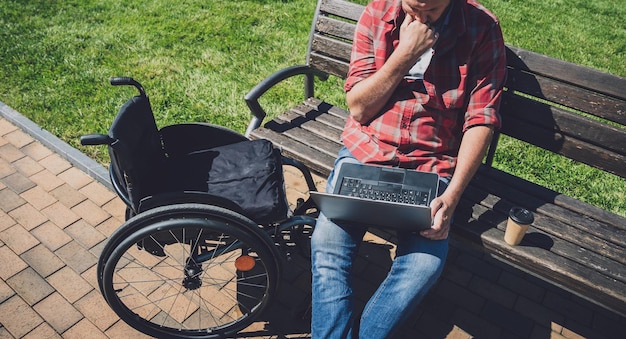 Freelancer z niepełnosprawnością ruchową na wózku inwalidzkim pracujący w parku