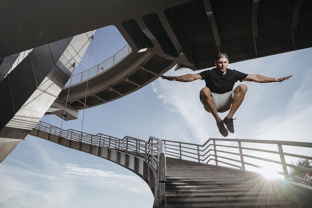 Zdjęcie freerunning sportowiec wykonujący piękny skok z mostu