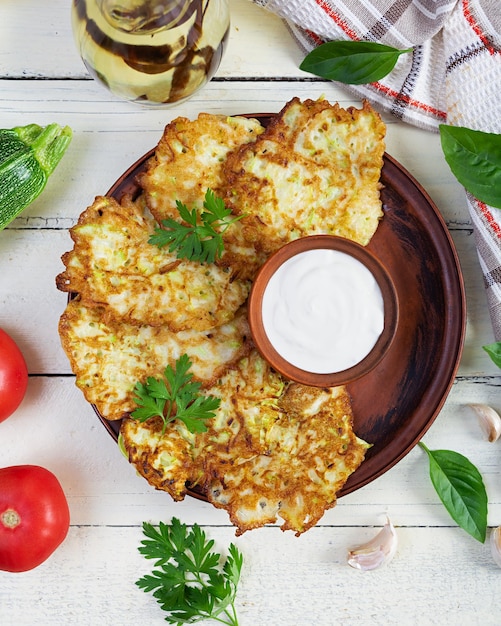 Fritry z cukini na talerzu z kwaśną śmietaną Pyszne ciastka z cukini