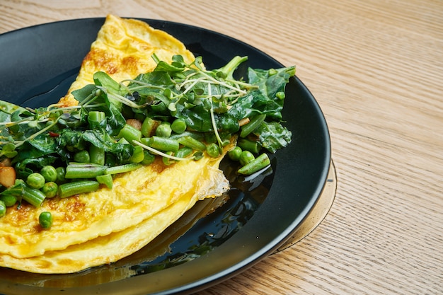 Zdjęcie frittata z grzybowym sosem pesto, rukolą i groszkiem na czarnej płycie. smaczny i zdrowy lunch. omlet