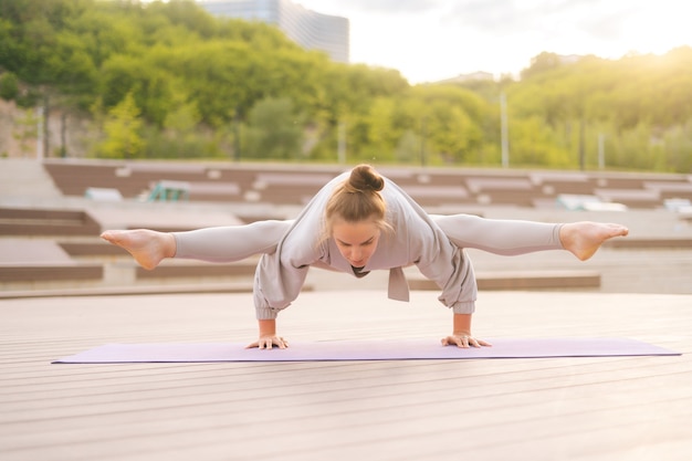 Fronv widok elastycznej młodej joginki ćwiczącej ćwiczących jogę na macie fitness w letni dzień