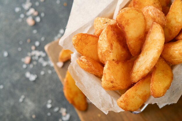 Frytki w metalowym drucianym koszu z solą i keczupem na starym drewnianym ciemnym tle clous up Smażone ziemniaki Koncepcja fast food i niezdrowej żywności