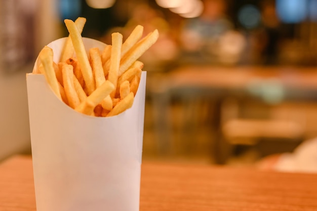 Frytki w papierowym koszu.Fast food.Frytki w białym papierowym pudełku