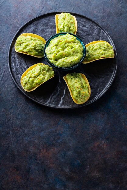 Frytki Z Guacamole Na Czarnym Talerzu. Meksykański Sos Guacamole Z Frytkami Na Ciemnym Tle. Koncepcja Meksykańskie Jedzenie W Kształcie Kwiatu. Skopiuj Miejsce. Widok Z Góry