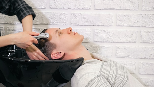 Zdjęcie fryzjer fryzjerski myje głowę mężczyzny