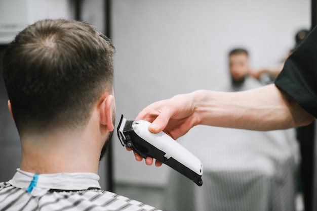Fryzjer goli młodą maszynkę do strzyżenia włosów Męskie fryzury w męskim salonie kosmetycznym