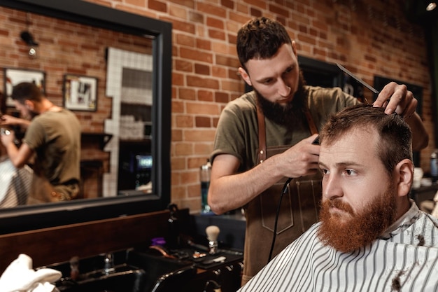 Fryzjer i brodaty mężczyzna w salonie fryzjerskim