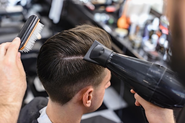 Fryzjer. Man Barber w męskim fryzjerze robi włosy nożyczkami.